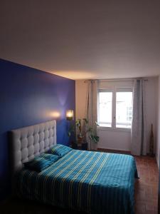 a bedroom with a bed with a blue wall and a window at Spacious Duplex Pantin, near Paris in Pantin