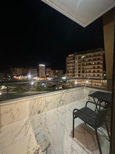 a table and a chair on a balcony at night at Bexhisteni lux rent in Shkodër