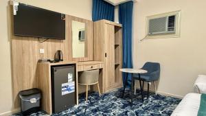a hotel room with a tv and a table and chairs at فندق جادة الغمامة in Medina