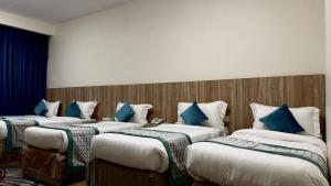 three beds in a room with blue pillows at فندق جادة الغمامة in Medina +17 photos