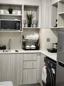 a kitchen with a sink and a microwave at Kave Embryo Pathum Thani Luxurious Condo in Ban Lam Phak Kut
