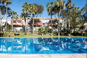 a large swimming pool with palm trees and houses at aldea 3 4 1ºB in Novo Sancti Petri