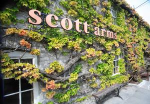 un edificio cubierto de hiedra con una señal en él en The Scott Arms, en Kingston