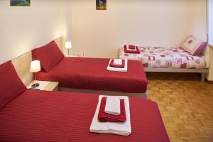two beds in a hotel room with red sheets at La Casa Di Fernanda in Belluno