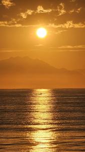 a sunset over the ocean with a boat in the water at O Paraiso é Aqui ! Casa de Hóspedes in Ubatuba