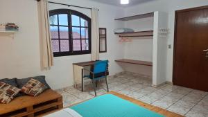 a room with a couch and a desk and a window at O Paraiso é Aqui ! Casa de Hóspedes in Ubatuba