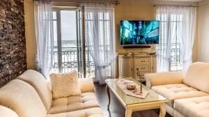 Sala de estar con 2 sofás blancos y TV en Apartamenty Zachód Słońca Mi Casa Holidays, en Mielno