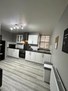 a kitchen with white cabinets and a wooden floor at Heart of Dalston East London in London