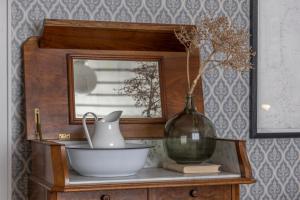 een tafel met een vaas, een kom en een spiegel bij Pater Noster A home on the horizon in Hamneskär