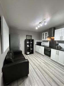 a living room with a black couch in a kitchen at Heart of Dalston East London in London