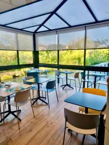 a cafeteria with tables and chairs and windows at Hotel Cantosorgue in L'Isle-sur-la-Sorgue