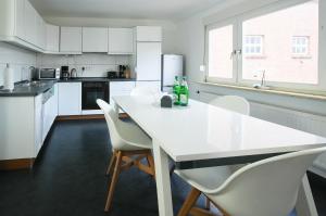 een witte keuken met een witte tafel en stoelen bij Ferienwohnung am Glück in Bad Zwischenahn