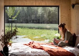 Una donna seduta su un letto che guarda fuori da una finestra di Wild Cabins Kinvara a Cloonnasee
