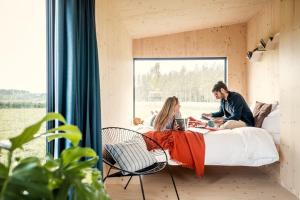 a man and woman sitting on a bed in a room at Wild Cabins Kinvara in Cloonnasee