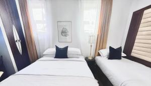 two beds in a room with white sheets and blue pillows at En-Suite Family Room Central London in London