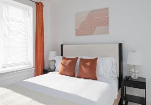 a bedroom with a bed with white sheets and orange pillows at Modern 2BR Comfort for 5 People - 20 Mins to NYC in West New York +17 photos