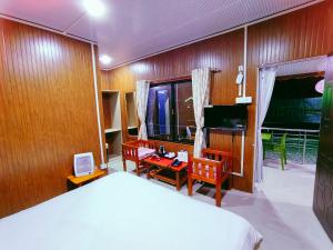 a bedroom with a bed and chairs and a television at HQ Resort in Ziro