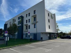 a large white building with a parking lot at B&B HOTEL Nantes Savenay in Savenay
