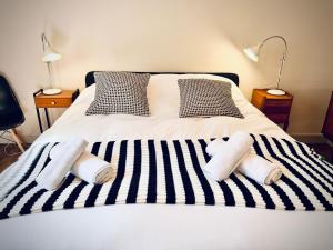 a bed with black and white striped sheets and pillows at Le JaKadi, Townhouse, Rennes city center in Rennes