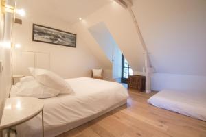 Habitación blanca con 2 camas y mesa en l'élégante, en Savennières