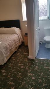 a bedroom with a bed and a toilet next to a door at Beachcomber Hotel in Blackpool