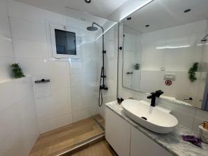 a white bathroom with a sink and a shower at Eleftherias Suites - Near Beach Apartments in Marathi