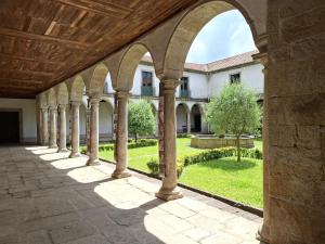 an arcade of a building with a garden in the background at Boanova Guesthouse Convento Cucujães in Oliveira de Azemeis