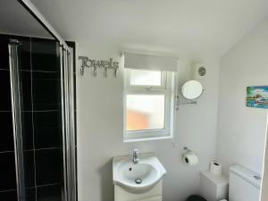 a bathroom with a sink and a toilet and a window at The Moorings in Wroxham +15 photos