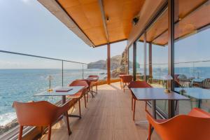 a restaurant with tables and chairs overlooking the ocean at Sentido Galomar - Adults Only in Caniço