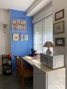 a kitchen with a table with a microwave and a blue wall at La Suzannerie in Vivoin