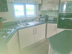 a kitchen with white cabinets and a sink at 'Falcons Rest' in Borth