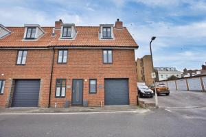 a brick house with two garage doors in a parking lot at Pebble Beach by the Sea in Deal