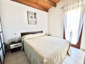 a white bedroom with a bed and a window at Villetta Flora with pool and private parking in Costa Paradiso