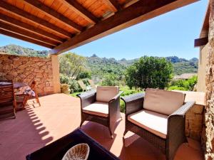 a patio with wicker chairs and a table with a view at Villetta Flora with pool and private parking in Costa Paradiso