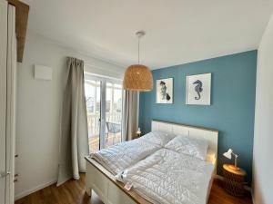 a bedroom with a bed and a blue wall at Salt & Sand Wohnung Sea in Haffkrug +17 photos
