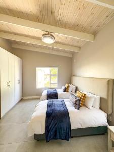 two beds in a large room with wooden ceilings at Slipway House Beachfront Villa in Britannia Bay