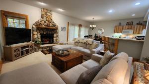 a living room with couches and a stone fireplace at Woods Way Hideaway - minutes from Petoskey & Harbor Springs - close to beaches, skiing & more! in Petoskey