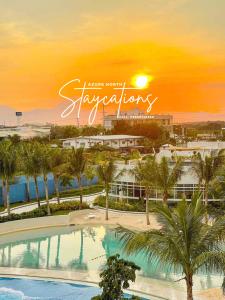 a view of a resort with a pool and palm trees at Modern Bali of Azure North in San Fernando