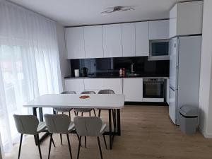 a white kitchen with a white table and chairs at Horizontes Azules -Apartments in Konjic