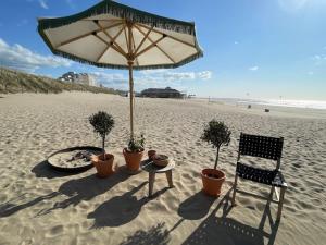 a table and a chair and an umbrella on the beach at ZeeBedStay in Noordwijk aan Zee
