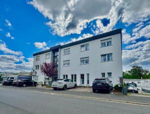 Un edificio blanco con coches aparcados delante. en AR Boutique Hotel Heusenstamm, en Heusenstamm