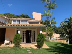 a house with a lawn and palm trees at Toca da Tartaruga 31, PISCINA PRIVATIVA EXCLUSIVA in Armacao dos Buzios