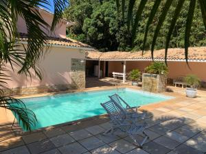 a swimming pool with two chairs and a house at Toca da Tartaruga 31, PISCINA PRIVATIVA EXCLUSIVA in Armacao dos Buzios