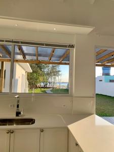 Casa de frente para lagoa com vista deslumbrante e ambiente tranquilo في لاغونا: مطبخ مع حوض ونافذة كبيرة