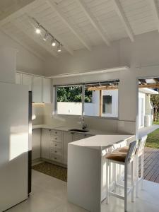 Casa de frente para lagoa com vista deslumbrante e ambiente tranquilo في لاغونا: مطبخ مع دواليب بيضاء وكاونتر مع كراسي