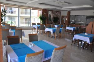 un restaurante con mesas y sillas azules y ventanas en Orion Park Residence, en Avsallar