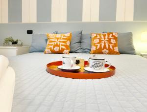 a bed with two cups and plates on it at Holihome - La Suite dei Fiori in San Benedetto del Tronto