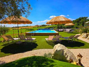 a yard with chairs and umbrellas and a swimming pool at Casa Cingoli in Cingoli