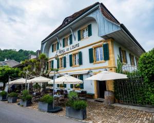 a building with tables and umbrellas in front of it at Romantik Hotel de L'Ours in Sugiez