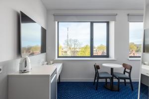 a kitchen with two chairs and a table and two windows at Roze Kurmajas Hotel in Liepāja